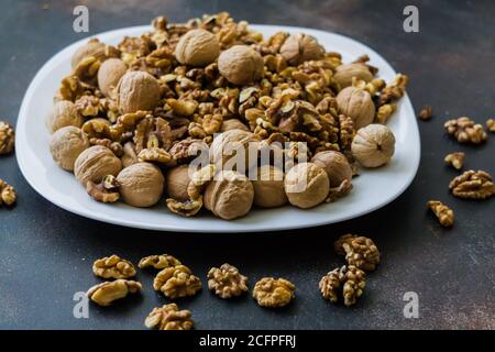 Walnuts peeled and in shells on a table in a plate Stock Photo