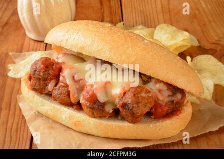 A meatball sandwich with potato chips on a brown wrapper Stock Photo