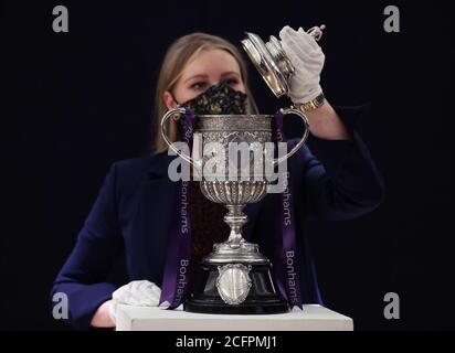 Laurel Kemp of Bonhams with the oldest surviving FA Cup trophy during a preview of the Sporting Trophies Sale at which will take place as Bonhams New Bond Street saleroom on September 29. The silver two-handled cup, estimated at GBP 700,000 -900,000, was made by Vaughton and Sons of Birmingham in 1896, and was presented to the FA Cup winning teams between 1896 and 1910, including Manchester United, Manchester City, Everton, Newcastle United and Tottenham Hotspur. Stock Photo