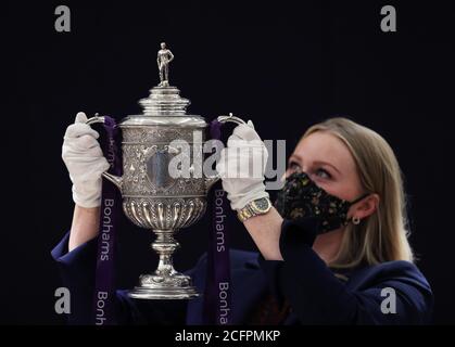 Laurel Kemp of Bonhams with the oldest surviving FA Cup trophy during a preview of the Sporting Trophies Sale at which will take place as Bonhams New Bond Street saleroom on September 29. The silver two-handled cup, estimated at GBP 700,000 -900,000, was made by Vaughton and Sons of Birmingham in 1896, and was presented to the FA Cup winning teams between 1896 and 1910, including Manchester United, Manchester City, Everton, Newcastle United and Tottenham Hotspur. Stock Photo