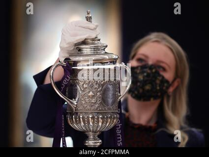 Laurel Kemp of Bonhams with the oldest surviving FA Cup trophy during a preview of the Sporting Trophies Sale at which will take place as Bonhams New Bond Street saleroom on September 29. The silver two-handled cup, estimated at GBP 700,000 -900,000, was made by Vaughton and Sons of Birmingham in 1896, and was presented to the FA Cup winning teams between 1896 and 1910, including Manchester United, Manchester City, Everton, Newcastle United and Tottenham Hotspur. Stock Photo