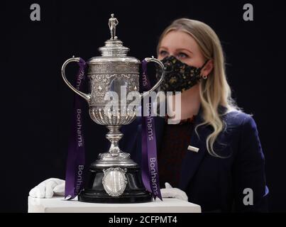 Laurel Kemp of Bonhams with the oldest surviving FA Cup trophy during a preview of the Sporting Trophies Sale at which will take place as Bonhams New Bond Street saleroom on September 29. The silver two-handled cup, estimated at GBP 700,000 -900,000, was made by Vaughton and Sons of Birmingham in 1896, and was presented to the FA Cup winning teams between 1896 and 1910, including Manchester United, Manchester City, Everton, Newcastle United and Tottenham Hotspur. Stock Photo