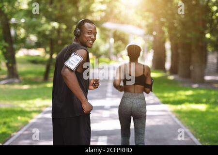 Sport Training. Black Athlete Guy Running With Female Fitness Partner In Park Stock Photo