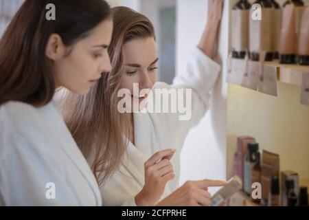 Two pretty women discussing beauty products in salon Stock Photo