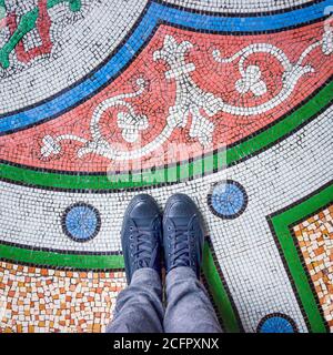 Feet selfie with black shoes on colorful beautiful mosaic tiles floor, top view Stock Photo