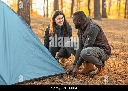 Man and woman making tent together, having conversation Stock Photo