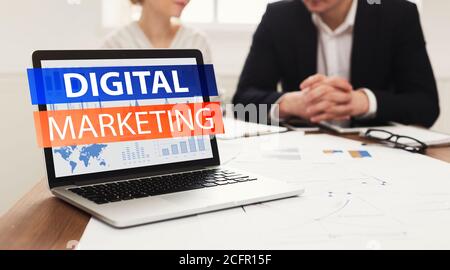 Laptop with digital marketing inscription over two workers Stock Photo