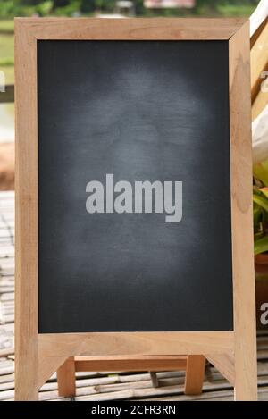 Black blackboard on wooden easel rubbed out dirty chalkboard on outdoors Stock Photo