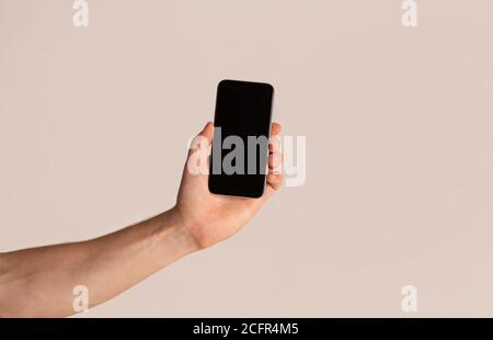 Male hand presenting smartphone with blank screen over light background, mockup for design Stock Photo