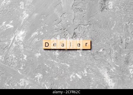 Dealer word written on wood block. Dealer text on cement table for your desing, concept. Stock Photo