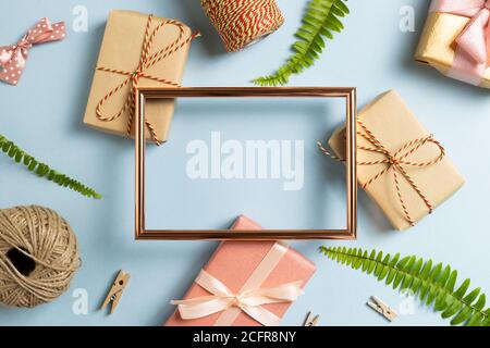 Gift wrapping concept. Empty photo frame with gift boxes on sky blue background. top view, copy space Stock Photo