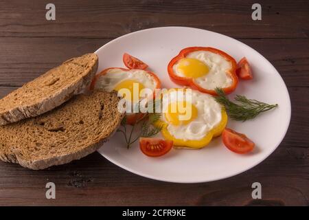 Scrambled eggs fried in rings of Bulgarian pepper with tomatoes and herbs. Stock Photo
