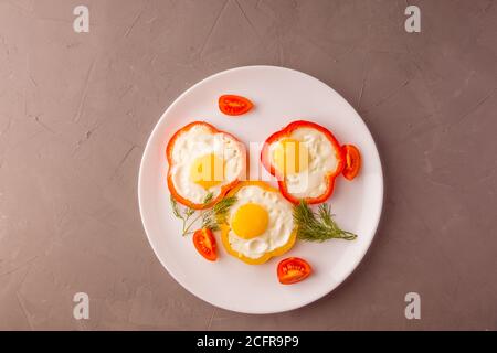 Scrambled eggs fried in rings of Bulgarian pepper with tomatoes and herbs. Stock Photo