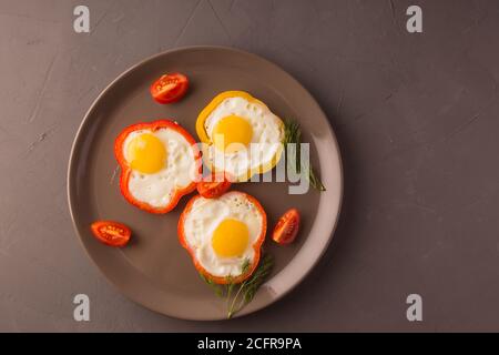 Scrambled eggs fried in rings of Bulgarian pepper with tomatoes and herbs. Stock Photo