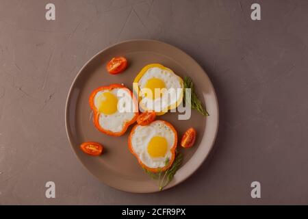 Scrambled eggs fried in rings of Bulgarian pepper with tomatoes and herbs. Stock Photo