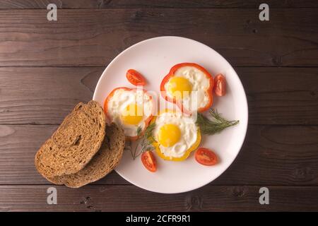 Scrambled eggs fried in rings of Bulgarian pepper with tomatoes and herbs. Stock Photo