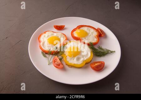Scrambled eggs fried in rings of Bulgarian pepper with tomatoes and herbs. Stock Photo