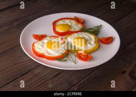 Scrambled eggs fried in rings of Bulgarian pepper with tomatoes and herbs. Stock Photo