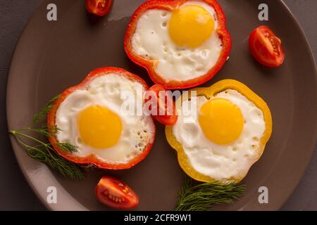 Scrambled eggs fried in rings of Bulgarian pepper with tomatoes and herbs. Stock Photo