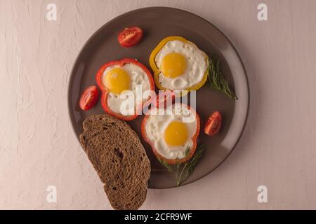 Scrambled eggs fried in rings of Bulgarian pepper with tomatoes and herbs. Stock Photo