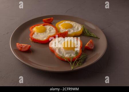 Scrambled eggs fried in rings of Bulgarian pepper with tomatoes and herbs. Stock Photo