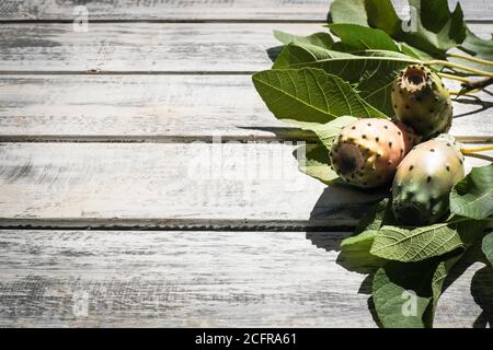 prickly pears nicely arranged on a white shabby chic wooden table with fig leaves, flat lay Stock Photo
