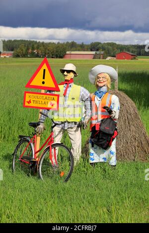 Funny arrangement of an couple with safety vests on alerts motorists of the Hiiden koulu school ahead. Pertteli, Salo, Finland.  September 6, 2020. Stock Photo