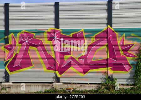 Purple,yellow and pink graffiti on a noise barrier wall Stock Photo