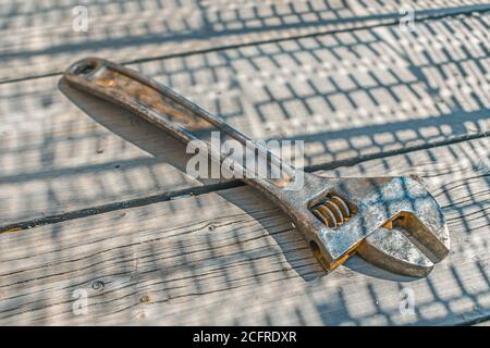 A rusty steel adjustable wrench lies on an old wooden floor Stock Photo
