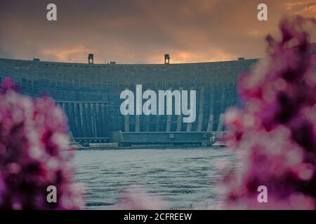 The dam of the Sayano-Shushenskaya hydroelectric power plant among lilac bushes. Stock Photo