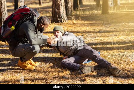 Black guy helping his injured friend while camping Stock Photo