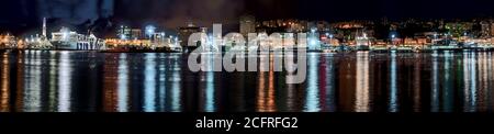 Panorama night view of the Old Port Genoa with reflections of the colorful lights from the waterfront buildings on the calm water and foreground copys Stock Photo