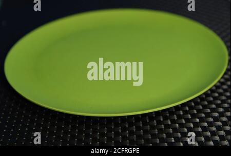 Green empty plate (oval plate) on a dark background. Household utensils. Acrylic plate used for food. Kitchen item. Stock Photo