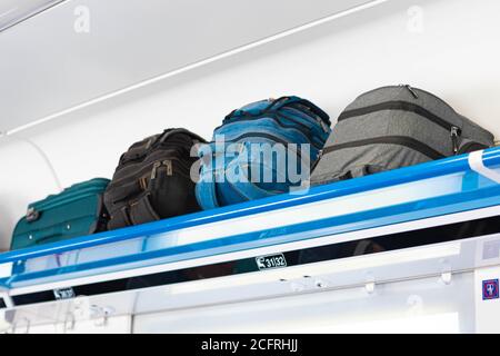 Carry-on luggage on the top shelf of the luggage compartment of an aircraft, train. Travel concept with copy space