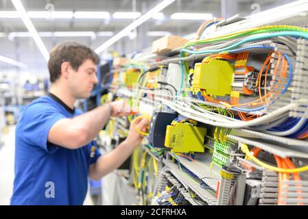 man assembles electronic components on a machine in a factory for mechanical engineering Stock Photo