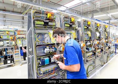 man assembles electronic components on a machine in a factory for mechanical engineering Stock Photo