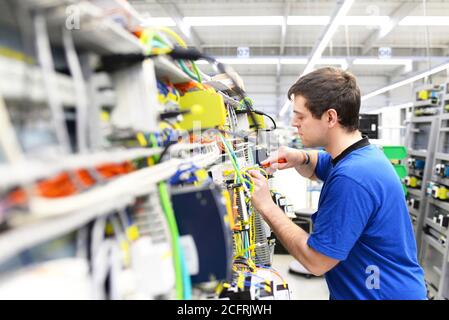 young apprentice worker in an industrial company assembling electronic components in the mechanical engineering of a modern factory Stock Photo
