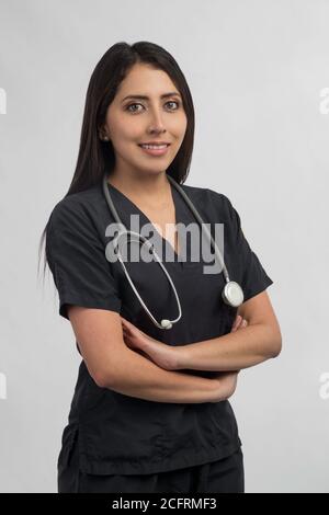 portrait of a young female doctor standing with stethoscope, using black uniform, studio with gray background Stock Photo