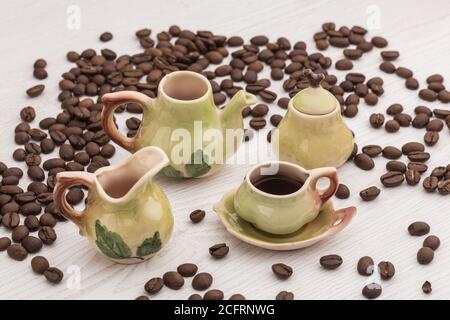 small set of porcelain cups with coffee beans on a wooden table and beans of coffee around Stock Photo