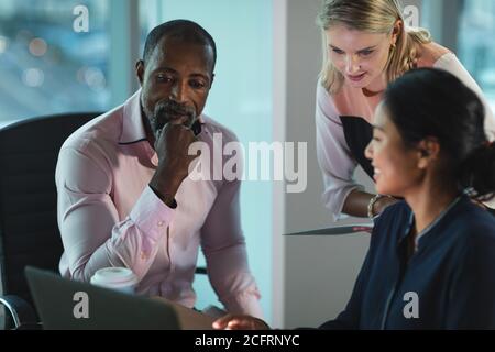 Senior businessman discussing with two young businesswoman at modern office