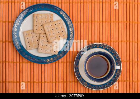 cup of  coffee with cookies, on blue porcelain set on an orange wooden texture, close up Stock Photo