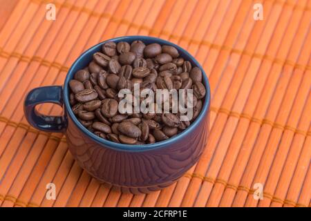 blue mug with coffee beans on an orange texture, studio Stock Photo