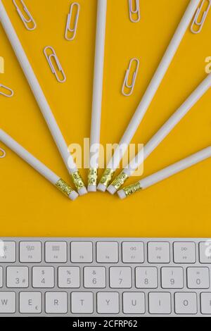 pencils, clips, and a keyboard, office objects on a yellow background,studio with yellow background Stock Photo