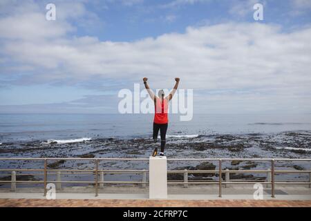 Rear view of man with prosthetic leg standing on the fence of the promenade Stock Photo