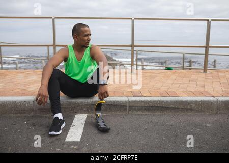 Man with prosthetic leg sitting on footpath Stock Photo