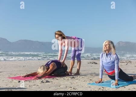 Yoga instructor teaching yoga to group of woman on the beach Stock Photo