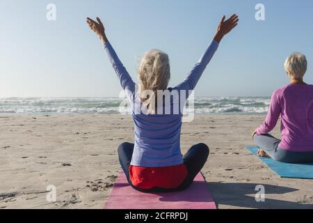 Rear view of mature woman practicing yoga pose in front of waterfall ...
