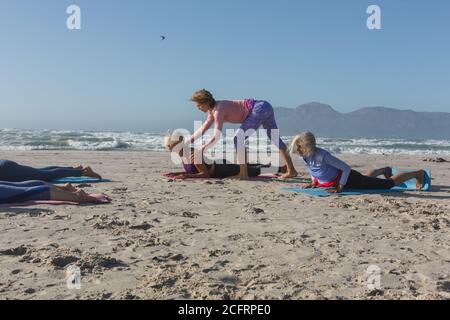 Yoga instructor teaching yoga to woman on the beach Stock Photo