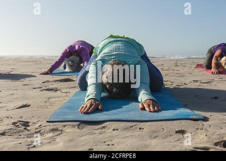 Group of woman practicing yoga on the beach Stock Photo
