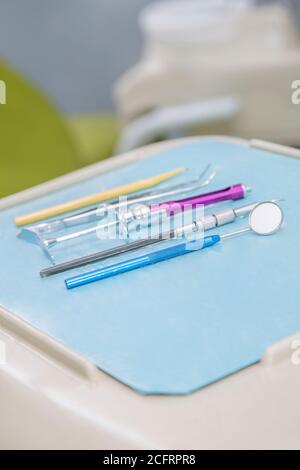 closeup of a dentist's tools of diferent colors and size on a blue table Stock Photo
